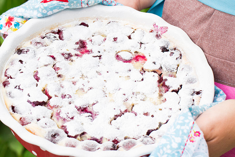 Kersenclafoutis in een schaal bestrooid met veel poedersuiker